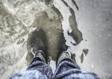 Mann in Gummistiefeln im Wasser